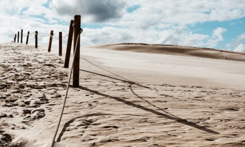 a sandy beach with a fence